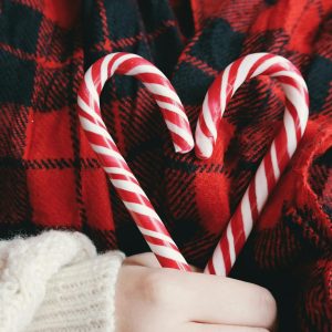 Close-up of a heart made from candy canes on a plaid blanket, perfect for winter holidays.